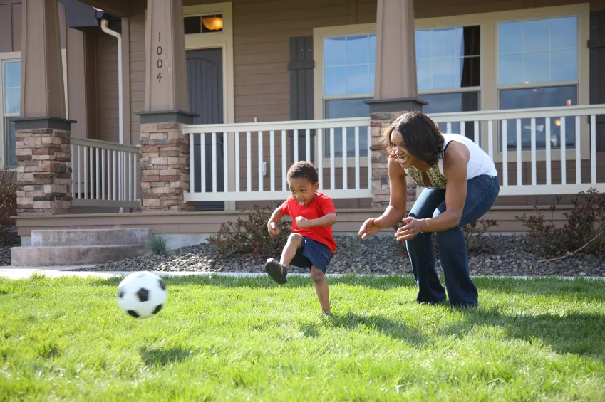 Boy and Mom playing soccer in grass